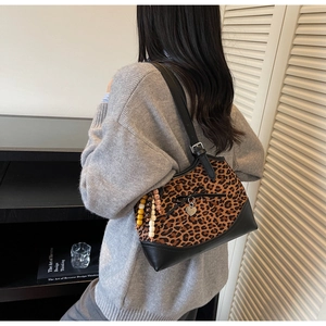 Close-up of leopard print shoulder bag with black leather trim and heart pendant
