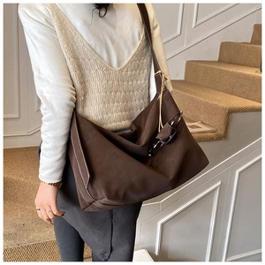 Detail of dark brown tote bag featuring white contrast stitching and unique buckle strap