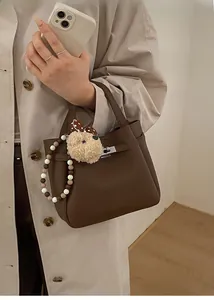 Close-up of dark brown lychee leather bucket bag with silver twist lock and furry charm