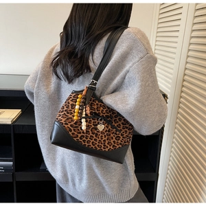 Detail view of large leopard print shoulder bag with black leather trim and bead heart charm