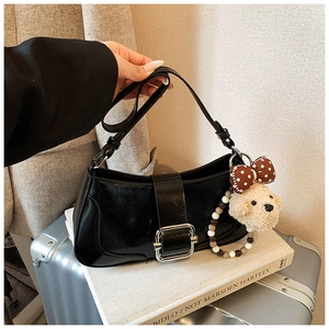 Détail du sac baguette noir brillant avec boucle argentée et breloque chien en peluche