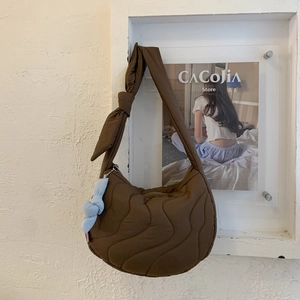 Close-up of brown quilted crossbody bag with wave stitching and knotted strap design