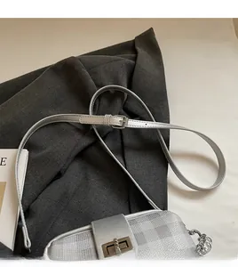 Detail of silver metallic handbag showing the adjustable long strap and metal twist lock