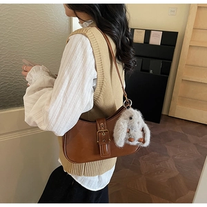 Detail of vintage brown leather shoulder bag with buckle and plush bunny charm