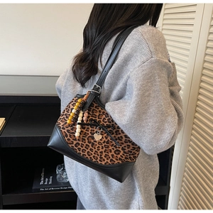 Detailed view of leopard print shoulder bag with decorative wooden beads on a model