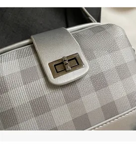 Close-up of silver checkerboard leather texture and metallic twist lock hardware