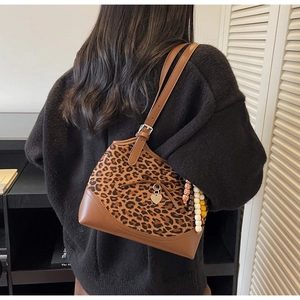 Detail of leopard print shoulder bag featuring a decorative bow and heart metal charm