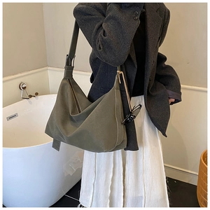 Detail of olive green canvas shoulder bag with white contrast stitching and zip closure