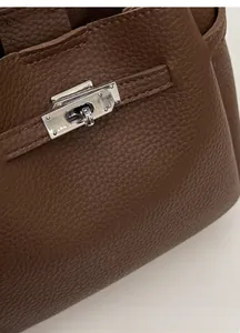 Close-up of brown litchi pattern leather bag with silver metal turn lock and stitching