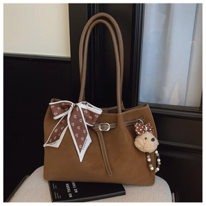Détail d'un sac cabas en cuir marron avec un foulard décoratif et un joli pendentif ourson