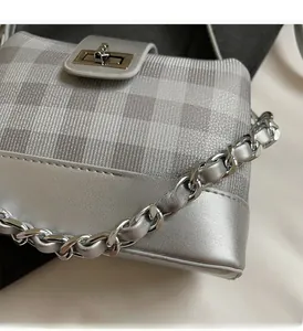 Close-up of silver leather and plaid fabric texture with a metal chain shoulder strap
