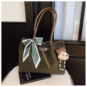 Détail du sac cabas en daim vert foncé avec foulard fleuri et breloque petit ours