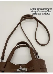 Detail of adjustable strap and silver buckle on brown lychee grain leather bucket bag
