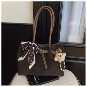 Détail d'un sac cabas en daim marron foncé avec foulard en soie et breloque ours doux