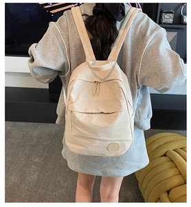 Détail d'un sac à dos en nylon beige léger avec texture froissée porté par un mannequin