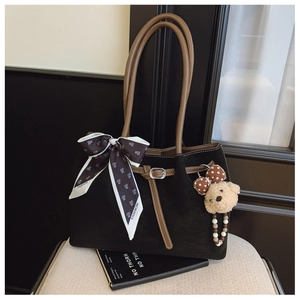 Détail du sac cabas noir avec anses brunes, foulard en soie et pendentif d'ourson
