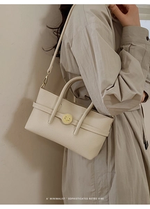 Detail of cream lychee leather texture and golden twist lock on a retro handbag