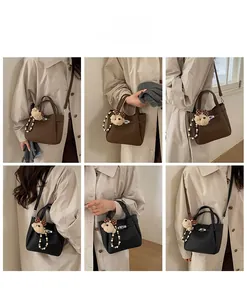 Detail view of lychee leather bucket bag with metal lock and cute bear charm pendant