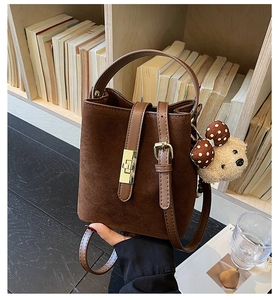 Detail of vintage brown suede bucket bag with gold buckle and cute plush bear charm