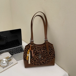 Close-up of leopard print handbag texture with wooden bead charms and leather straps
