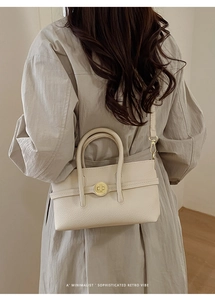 Detailed close-up of retro cream beige leather handbag with golden round rotary lock buckle
