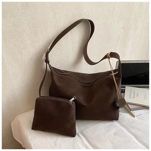 Detailed view of brown suede hobo tote bag set with matching pouch on a white desk