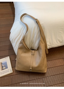 Close-up of a dark beige leather hobo bag with adjustable strap and silver ring detail