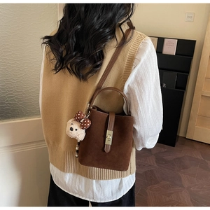 Brown suede bucket bag with leather strap and a cute beige teddy bear charm
