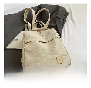 Vue détaillée du sac à dos en nylon beige avec poches cachées et logo en cuir M élégant