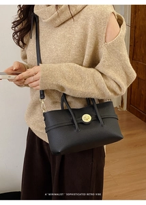 Detail of black lychee grain leather bag featuring a gold twist lock and fine stitching