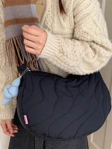 Black quilted puffer crossbody bag with wave stitching and light blue knot charm