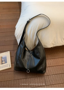 Detail of a black leather hobo bag featuring silver hardware and decorative stitching