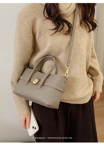 Detailed view of the taupe lychee texture leather handbag featuring a golden metal twist lock