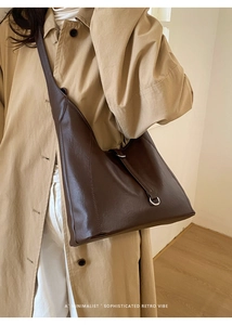 Detail of dark brown leather hobo bag with metal buckle and wide shoulder strap
