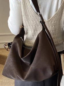 Deep brown oversized hobo shoulder bag with pleated texture and wide strap on model