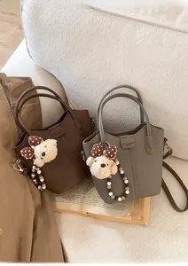 Detailansicht der Mini-Eimertaschen in Braun und Grau mit Plüschbär und Perlenkette