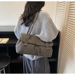 Detail of grey suede tote bag with woven shoulder strap and silver rivet trim accents