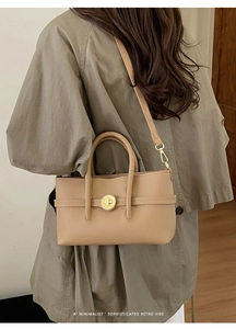 Close-up of litchi grain leather handbag featuring a vintage metal twist lock and dual handles