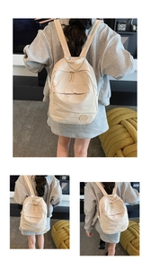 Détail du sac à dos beige en nylon avec écusson logo M et poche zippée à l'avant