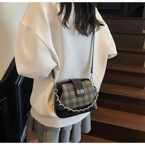 Detail of checkered crossbody bag with silver twist lock and decorative chain strap