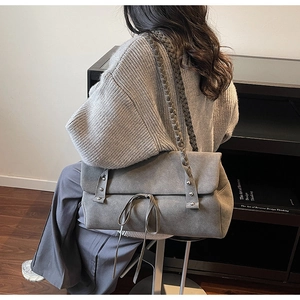 Detail showing grey faux-suede tote bag with woven handles, silver studs and bow decoration