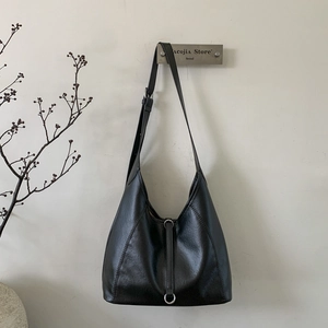 Detailed close-up of a minimalist black leather tote bag hanging on a modern hook