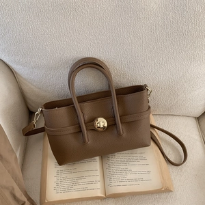 Detailed macro view of the brown lychee leather texture and golden twist lock closure