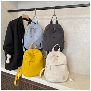 Détails des sacs à dos en nylon colorés bleu, gris, jaune et beige avec logos ronds