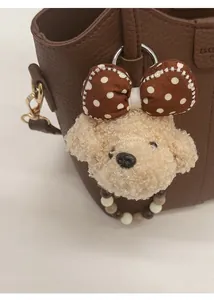 Detail eines Plüsch-Hundeanhängers mit gepunkteter Schleife an einer Ledertasche