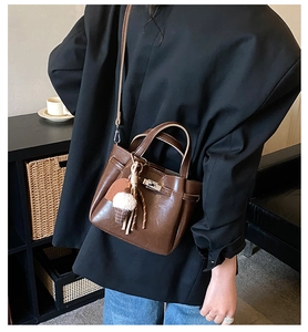 Detail of dark brown leather bucket bag with metal buckle and ice cream charm