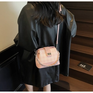 Pink checkered crossbody bag with silver twist lock and chain strap on a model