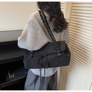 Detail of black tote bag with woven shoulder straps and bow knot decoration on model