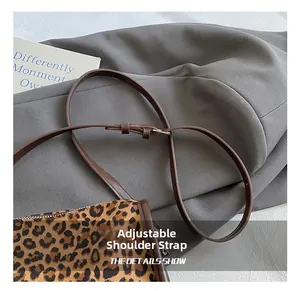 Detail of adjustable thin brown leather shoulder strap on leopard print crossbody bag