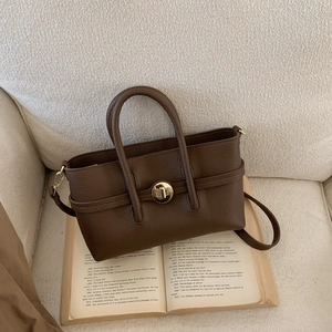Close-up of deep brown lychee texture leather handbag with golden round rotary lock
